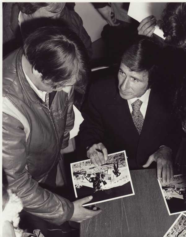 Black & White photo showing Jim Irwin signing a photograph